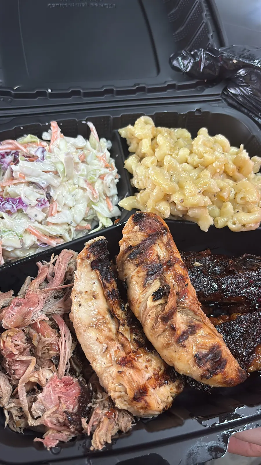 Takeout box with pulled pork, grilled chicken, coleslaw, and mac and cheese