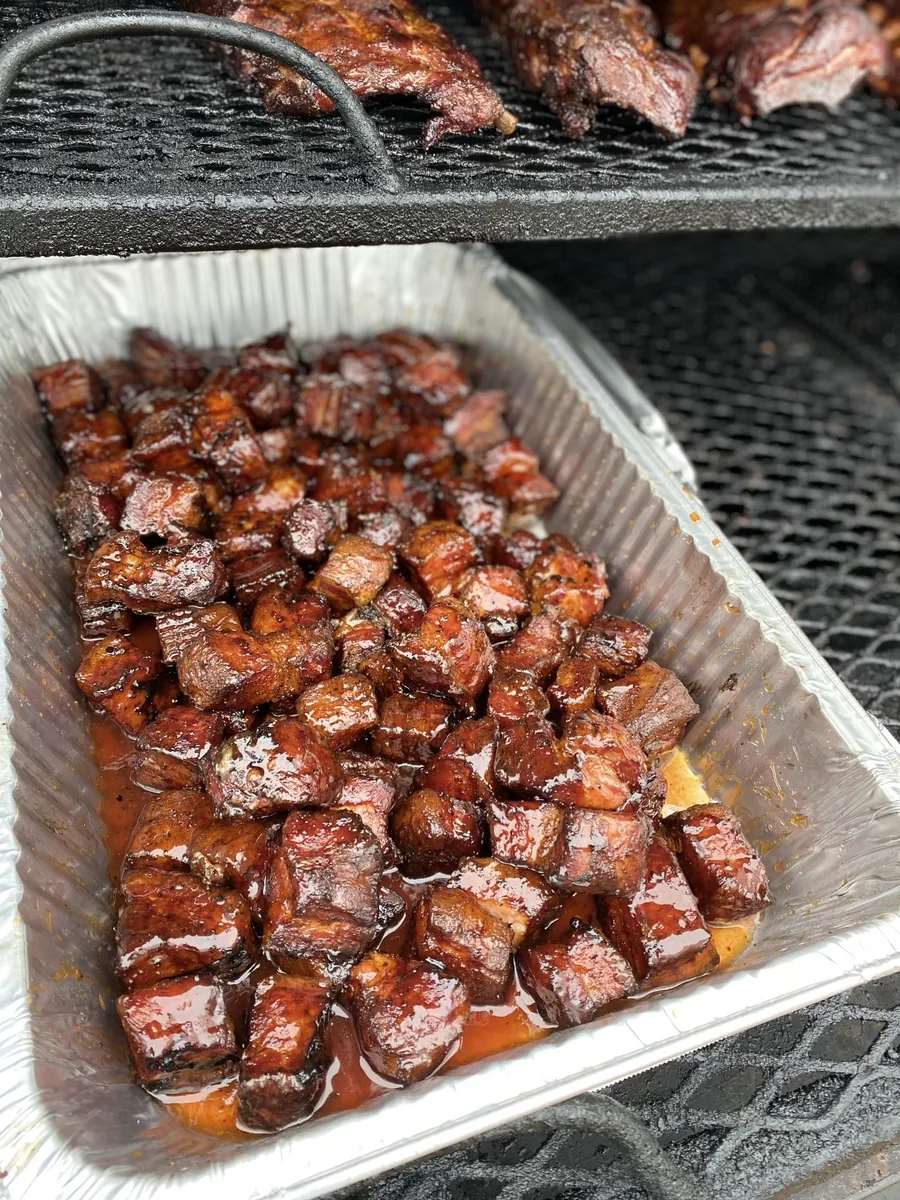 A pan of glazed pork belly burnt ends on the smoker