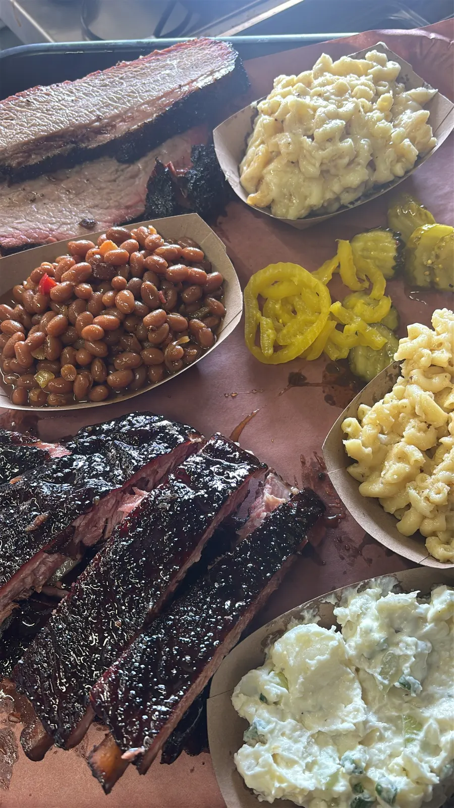 Glazed smoked ribs and sliced brisket with bowls of sides